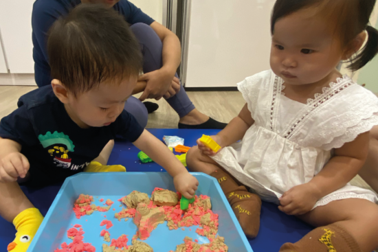 Toddlers engaging in sensory play through sand